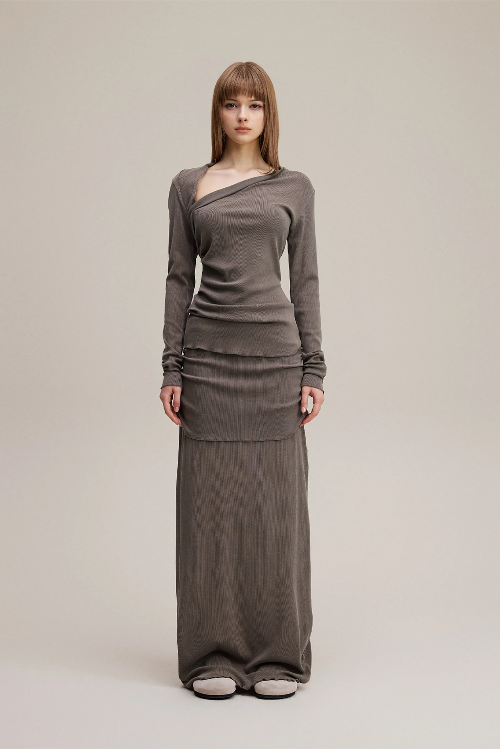 Woman wearing a long brown dress on a plain background