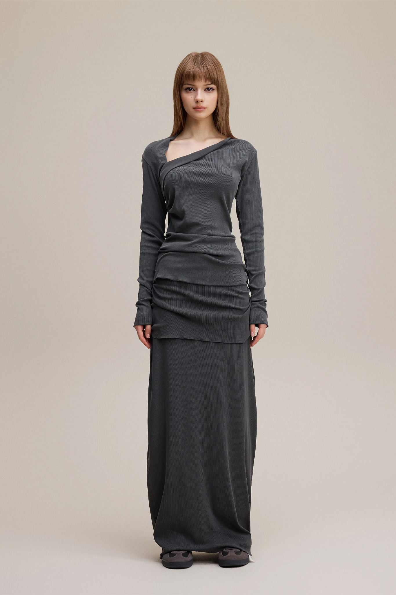 Woman wearing a long gray dress on a plain background