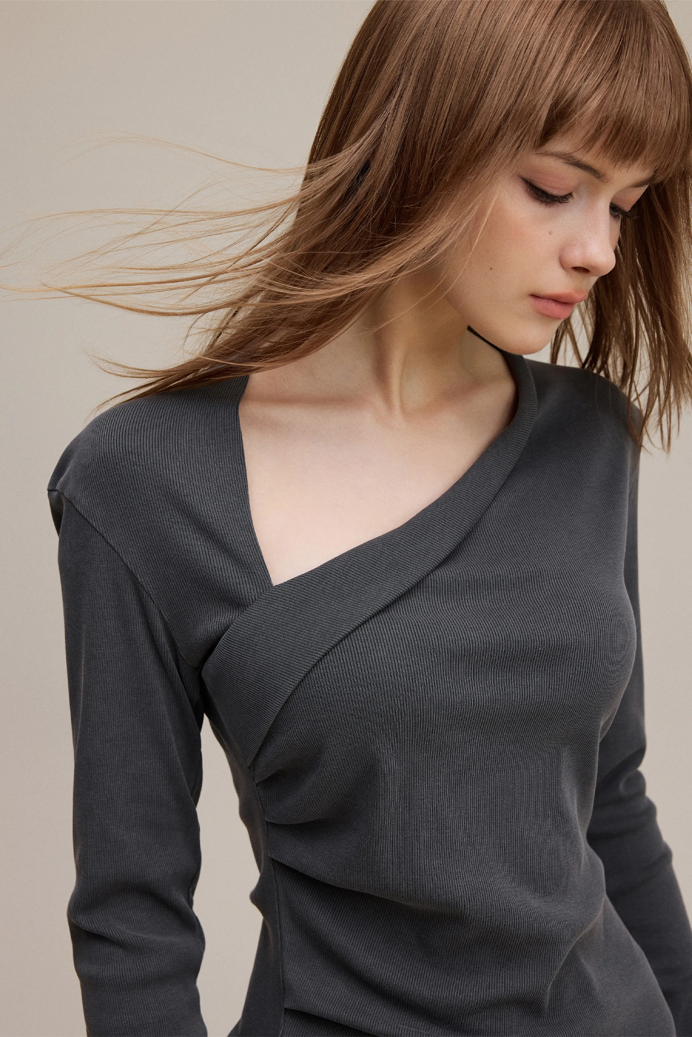 Woman wearing a dark gray long-sleeve top against a neutral background