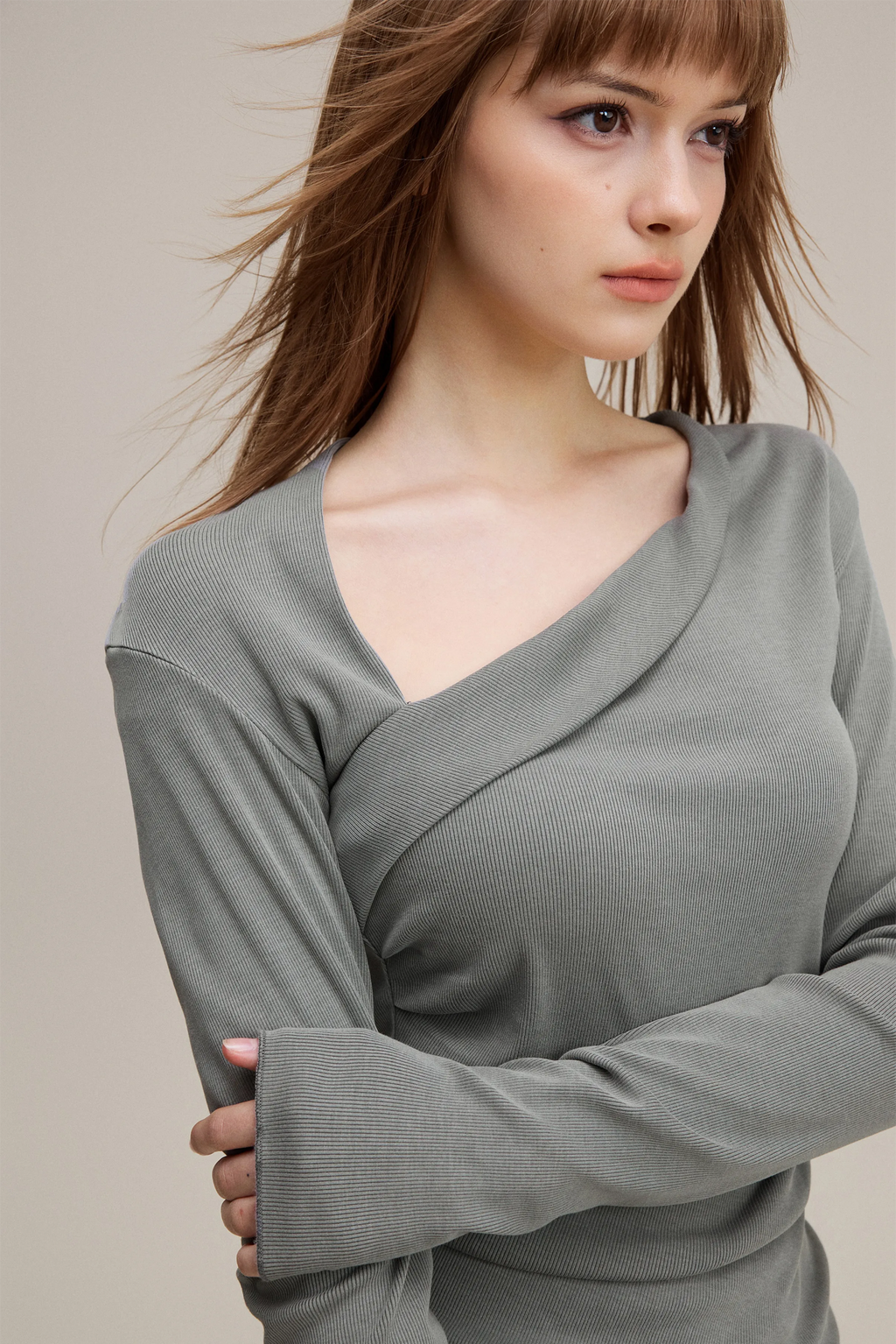 Woman wearing a gray long-sleeve top against a neutral background