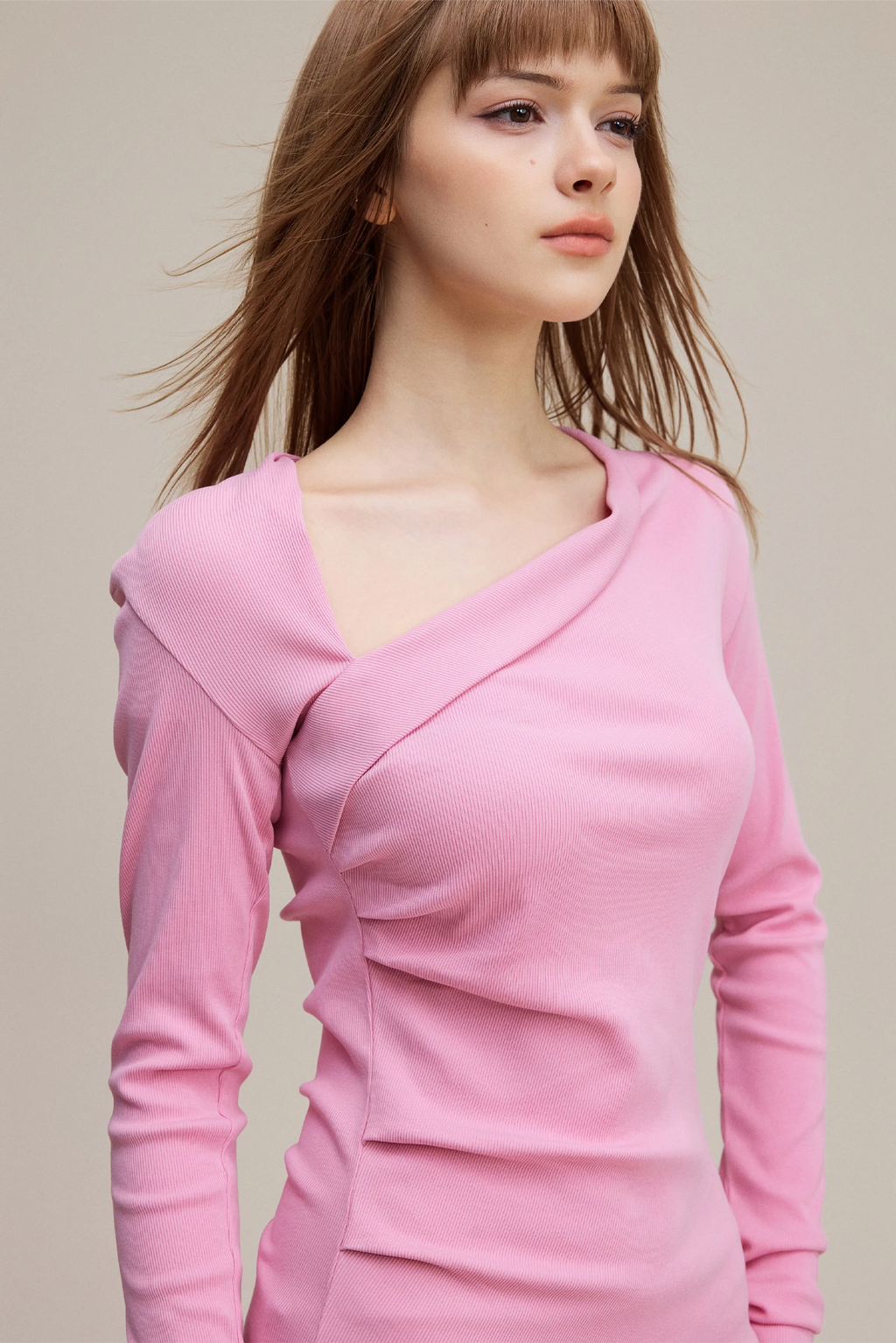Woman wearing a pink long-sleeve top against a neutral background