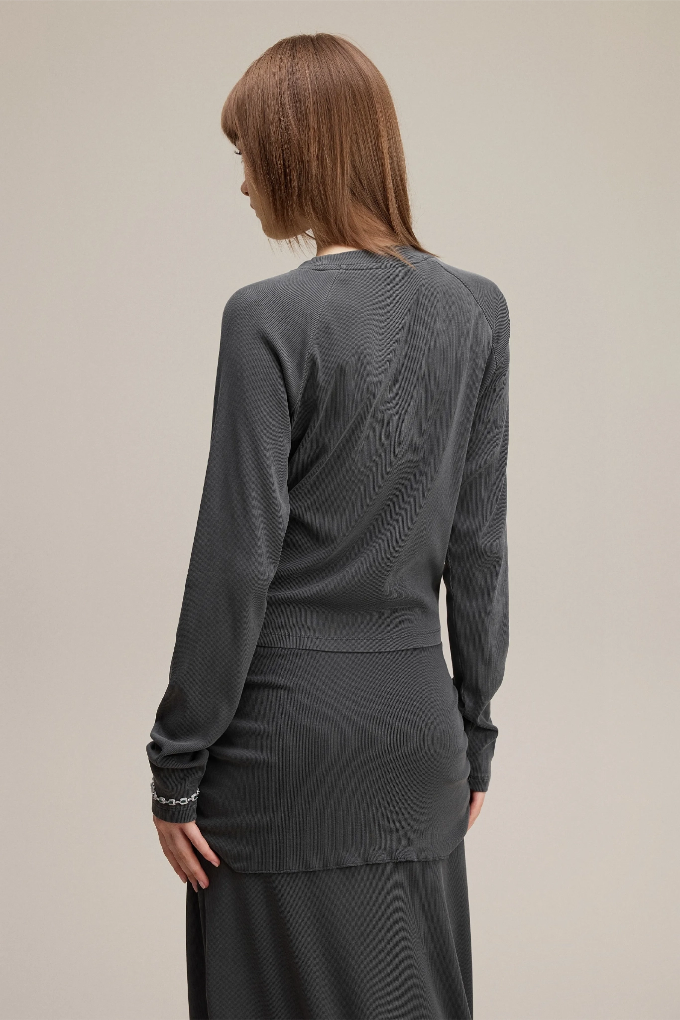 Woman wearing a gray long-sleeve top and skirt set on a beige background