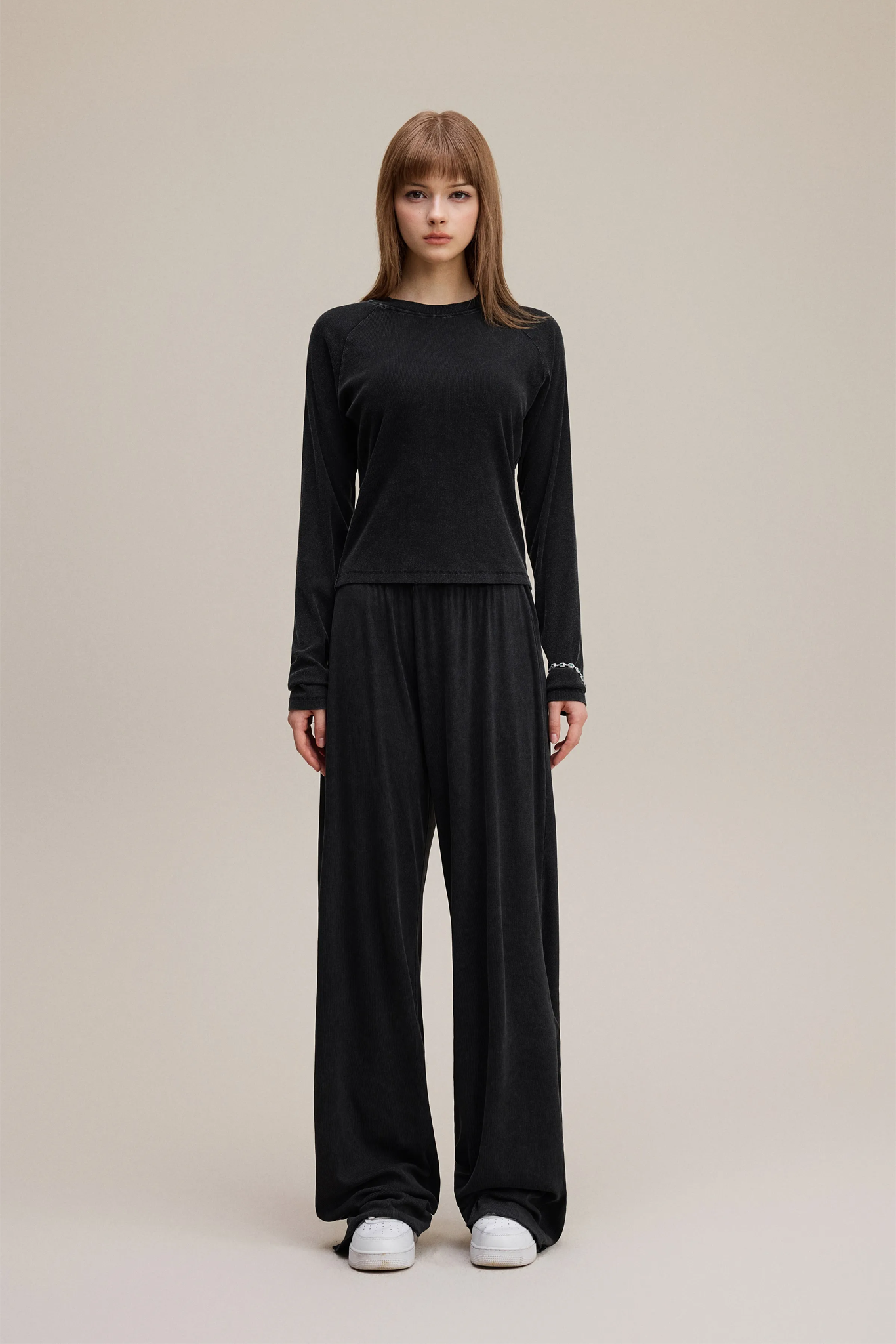 Person wearing a black outfit on a beige background