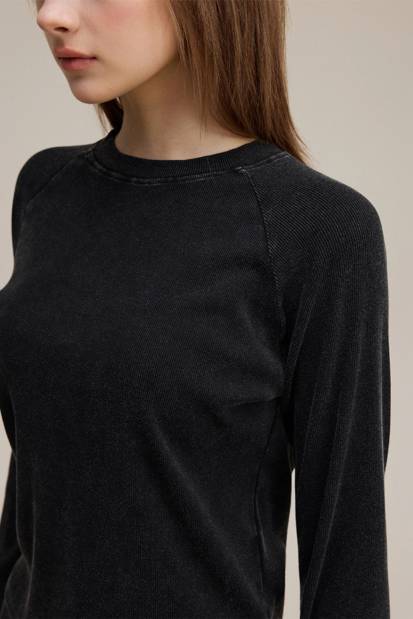 Black long-sleeve top worn by a person on a neutral background