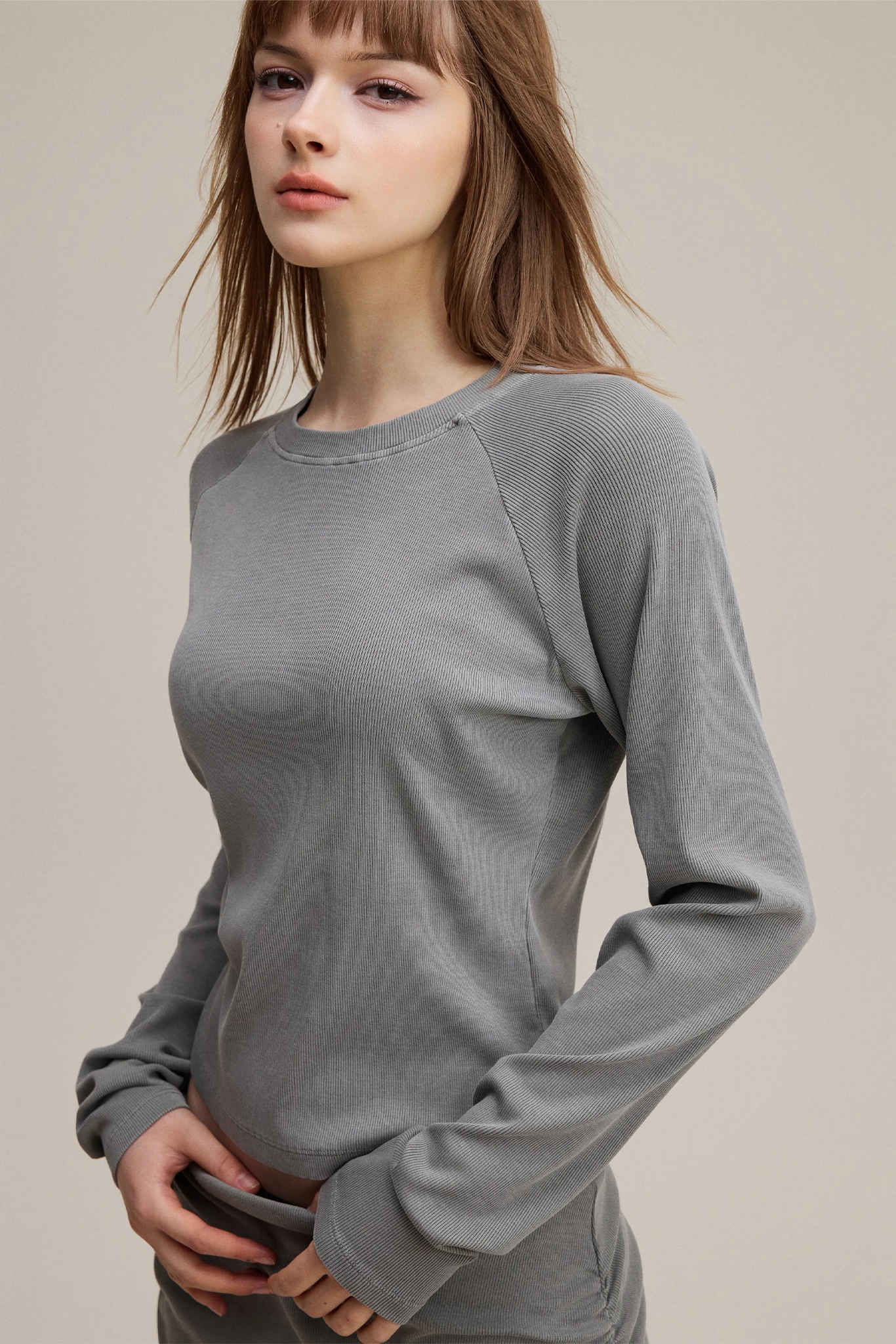 Woman wearing a gray long-sleeve top against a plain background
