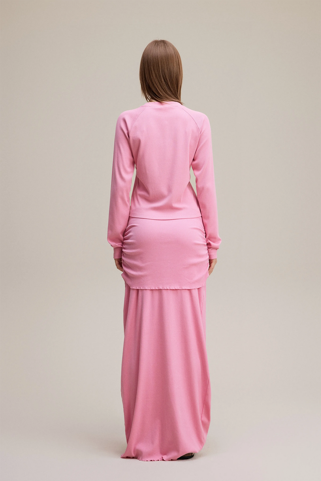 Person wearing a pink outfit on a beige background