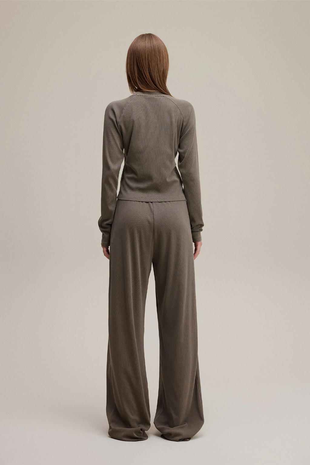 Person wearing a brown jumpsuit on a plain background