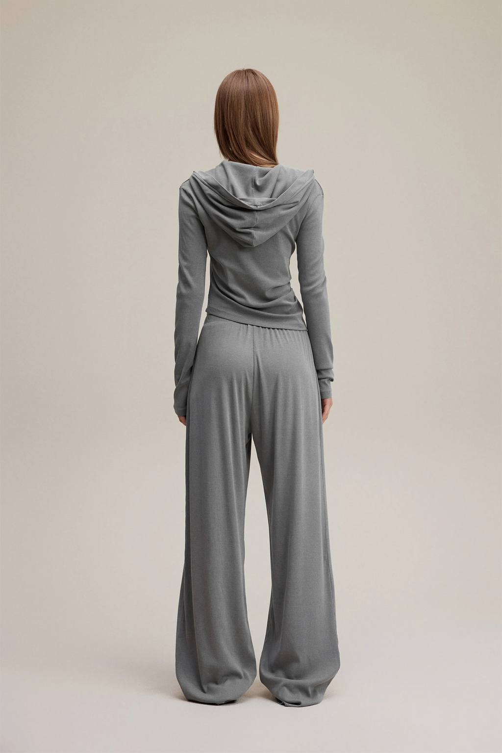 Person wearing a gray tracksuit on a beige background