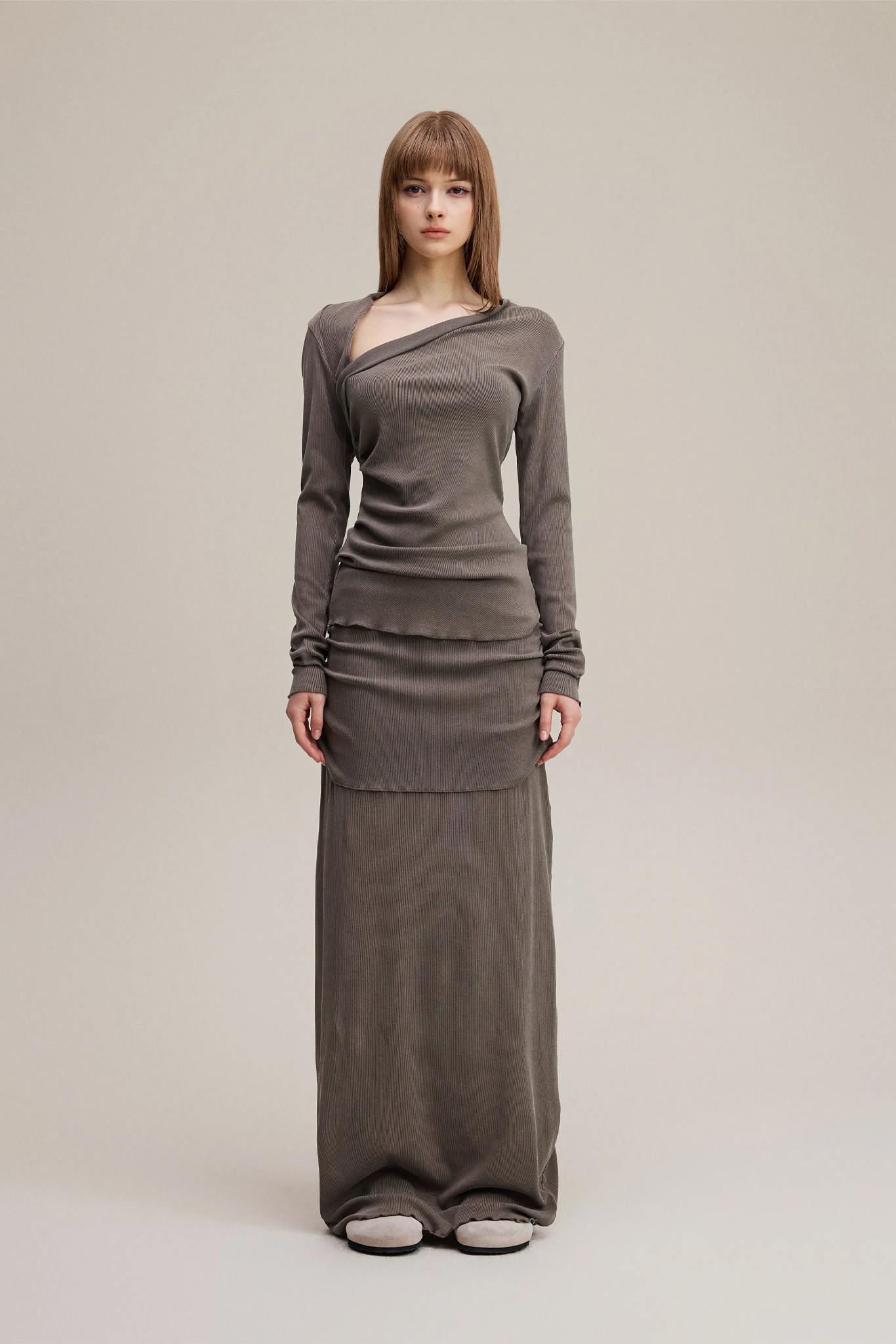 Woman wearing a long brown dress on a plain background