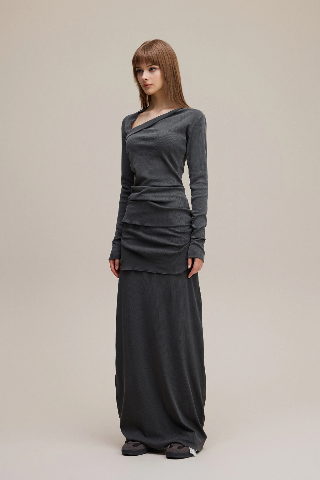 Woman wearing a long dark gray dress on a plain background