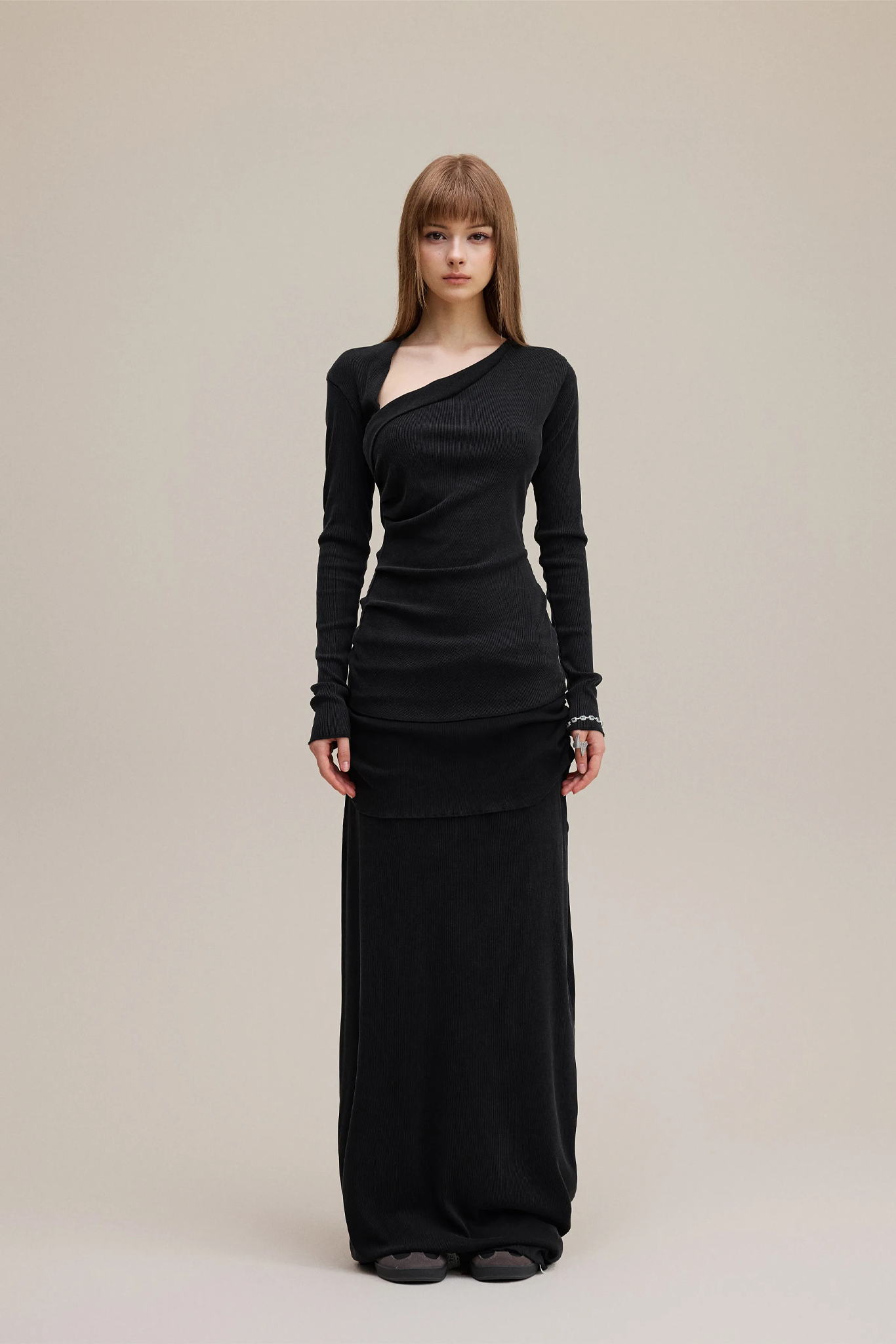 Woman wearing a black long-sleeve dress against a beige background