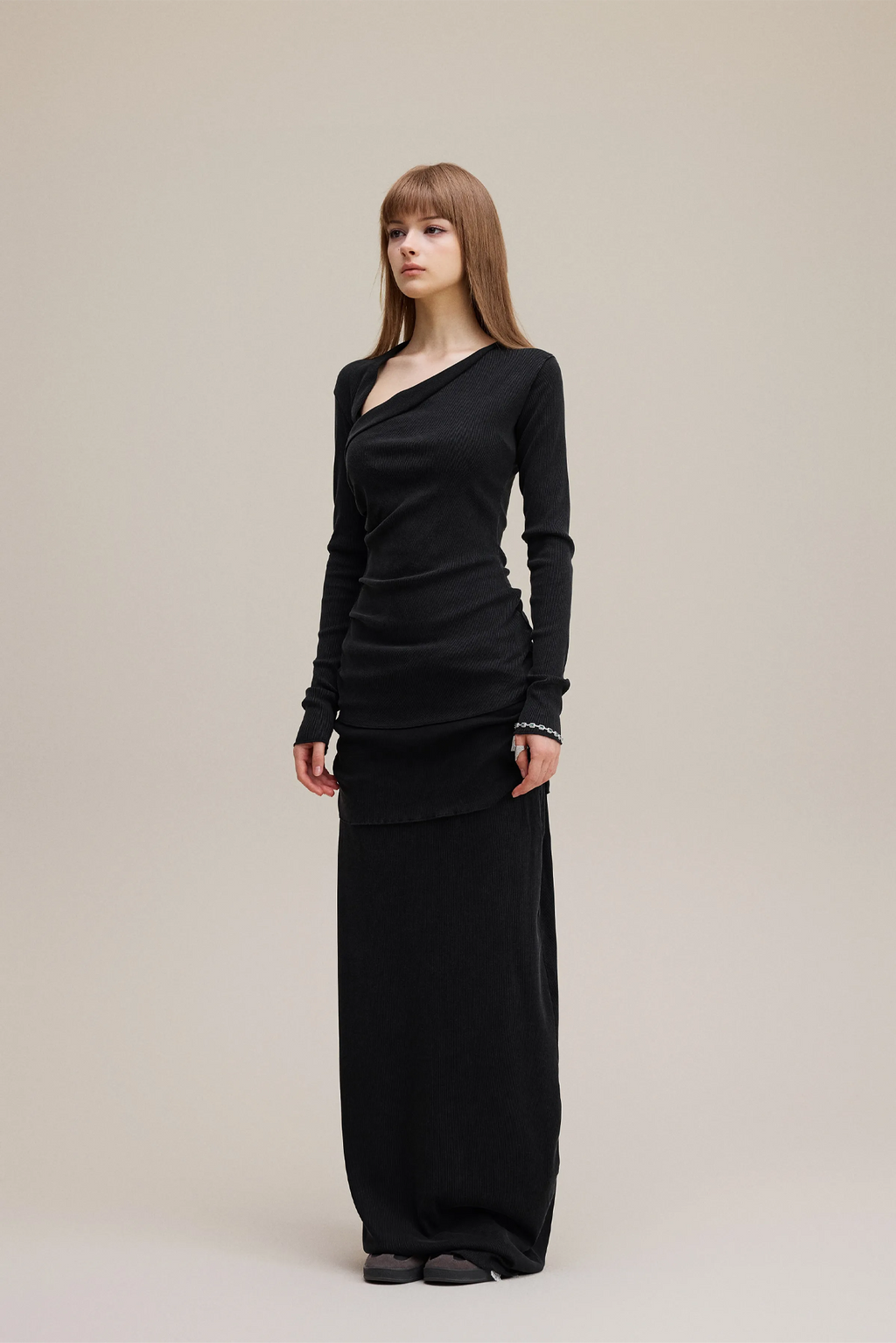 Woman wearing a black long-sleeve dress against a beige background