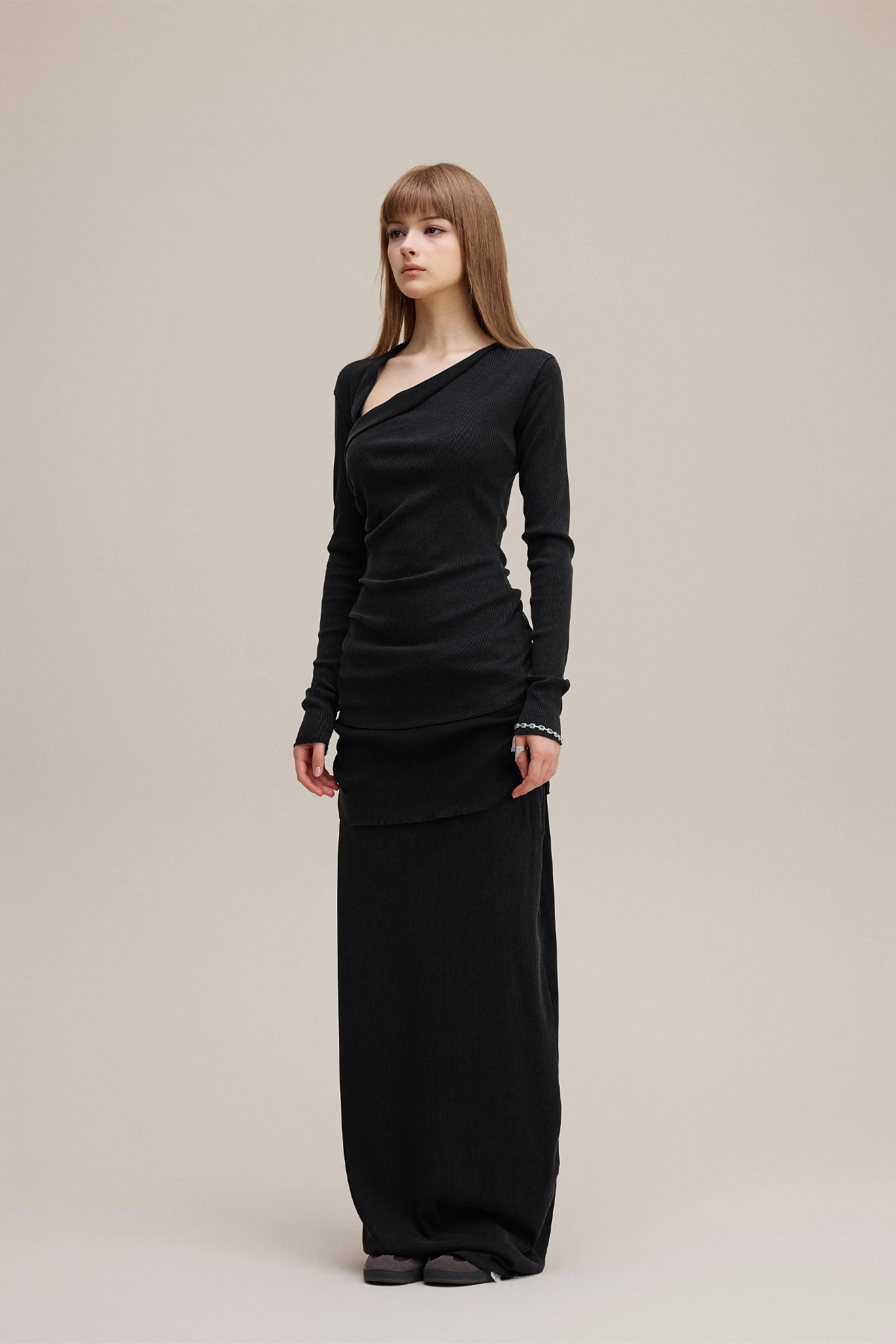 Woman wearing a black long-sleeve dress against a beige background