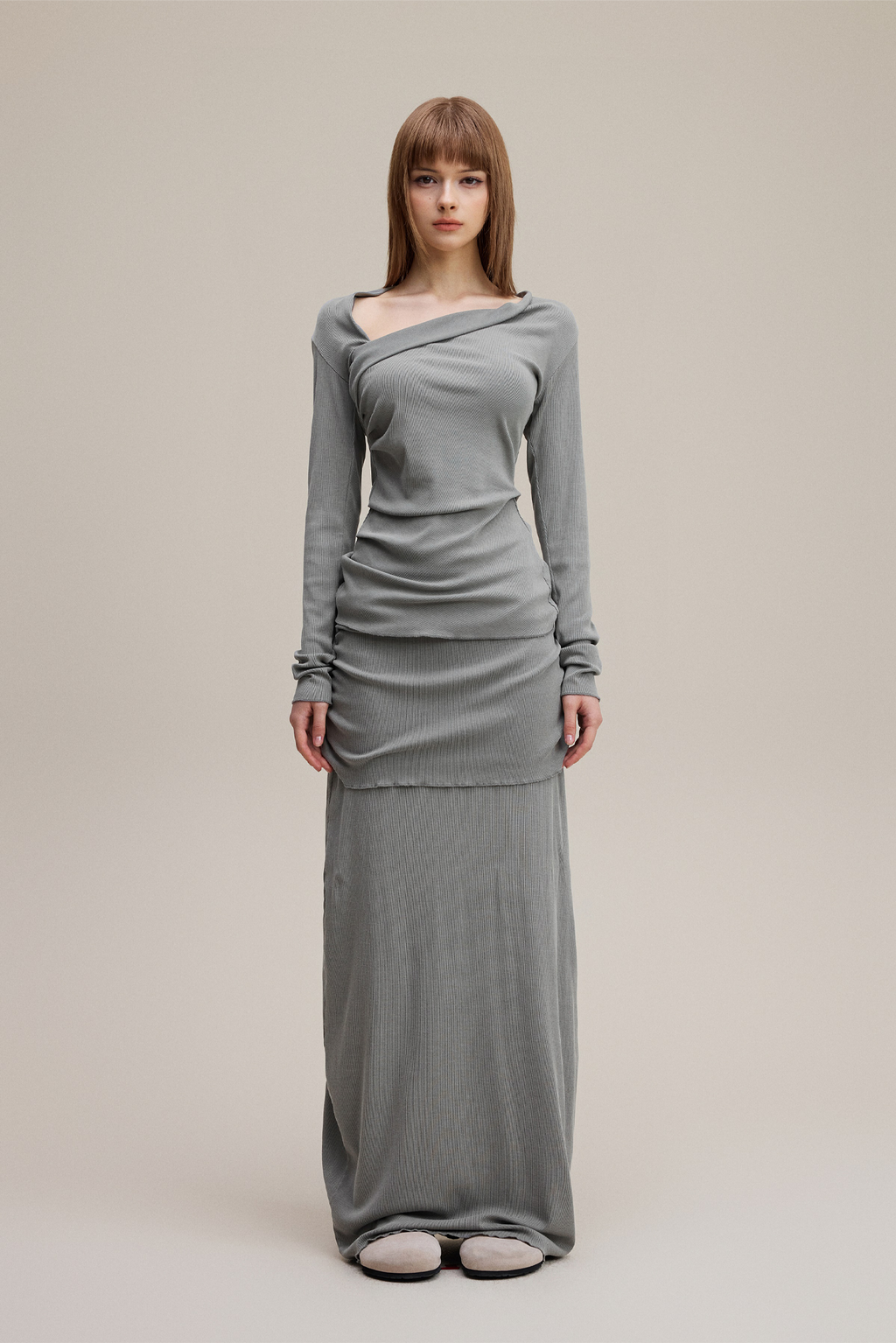 Woman wearing a gray long-sleeve dress on a plain background