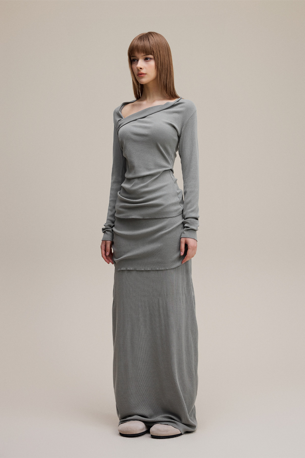 Woman wearing a long gray dress against a plain background