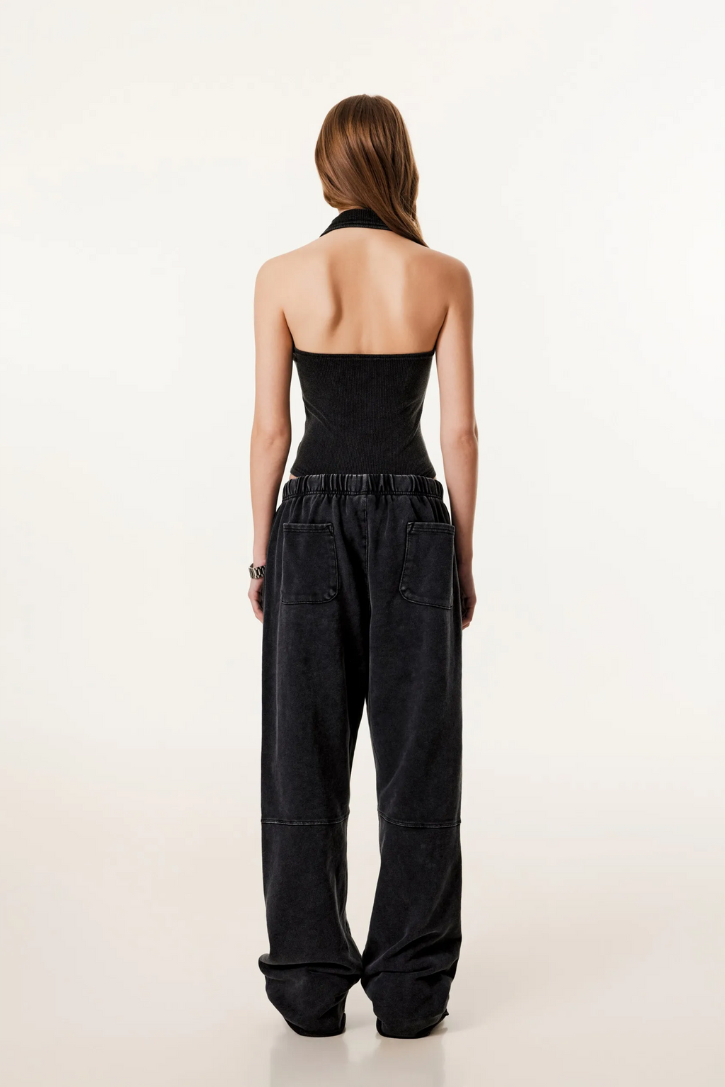 Woman wearing a black strapless jumpsuit on a white background