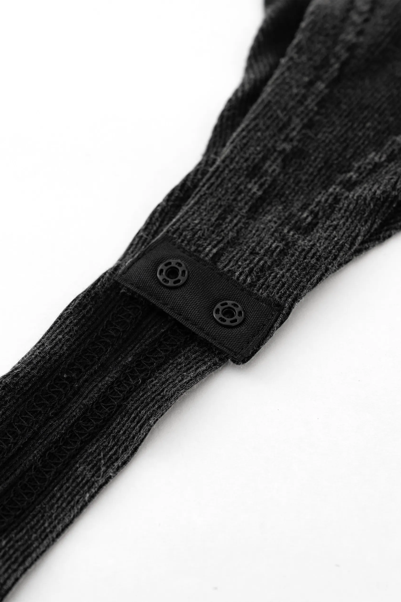 Black knit sock with a button on a white background