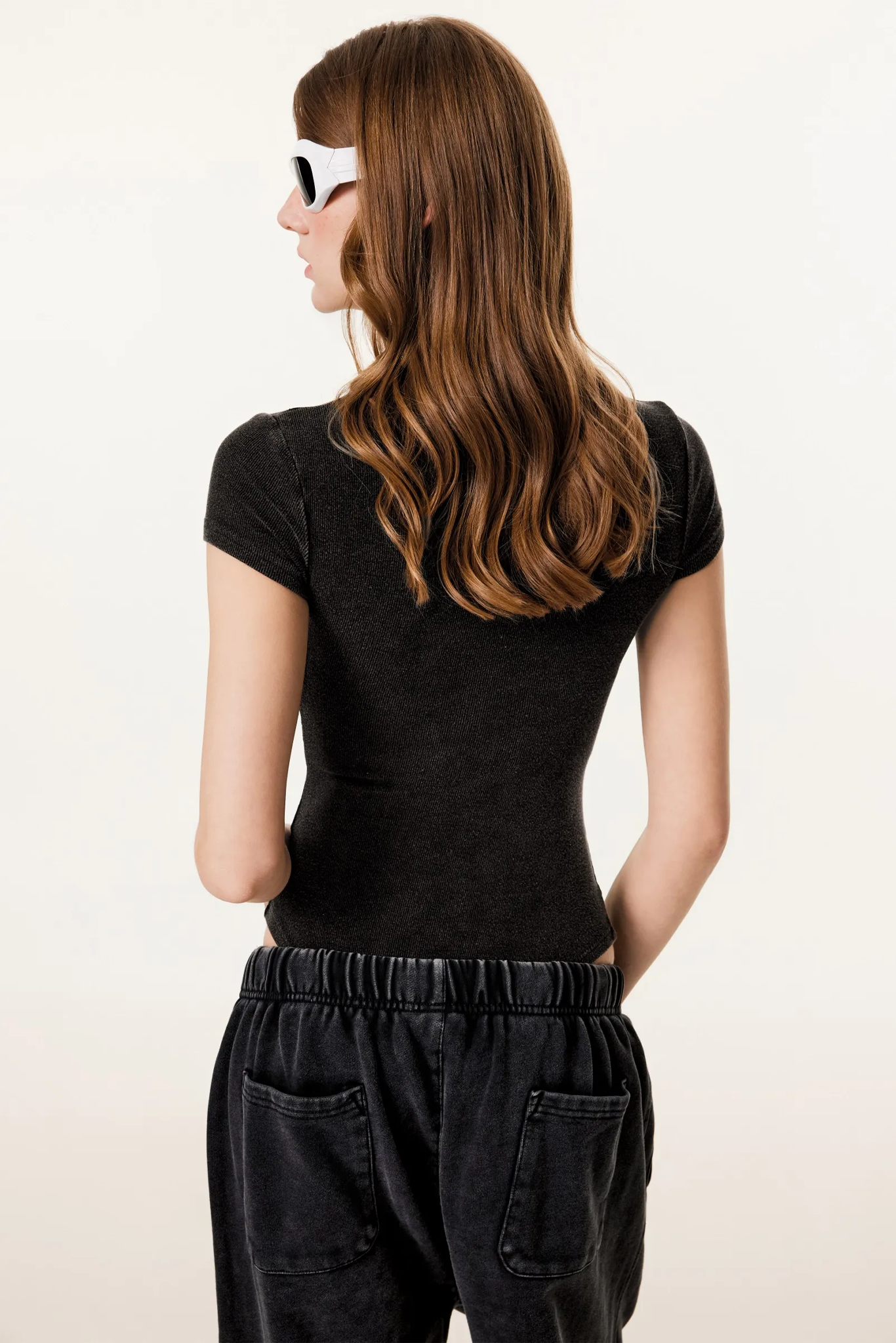 Woman wearing a black t-shirt and dark pants on a white background