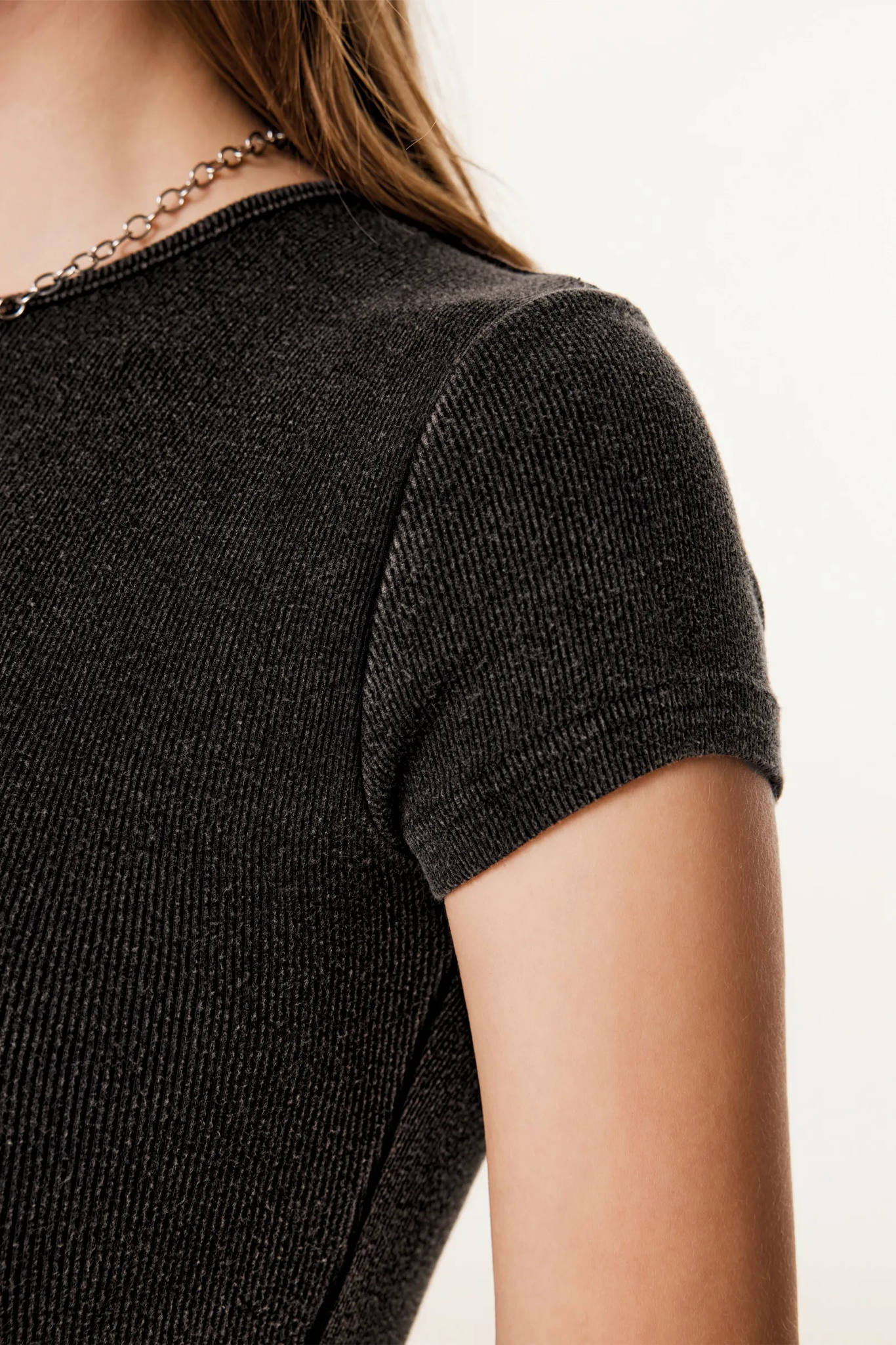 Close-up of a person wearing a black textured top on a white background