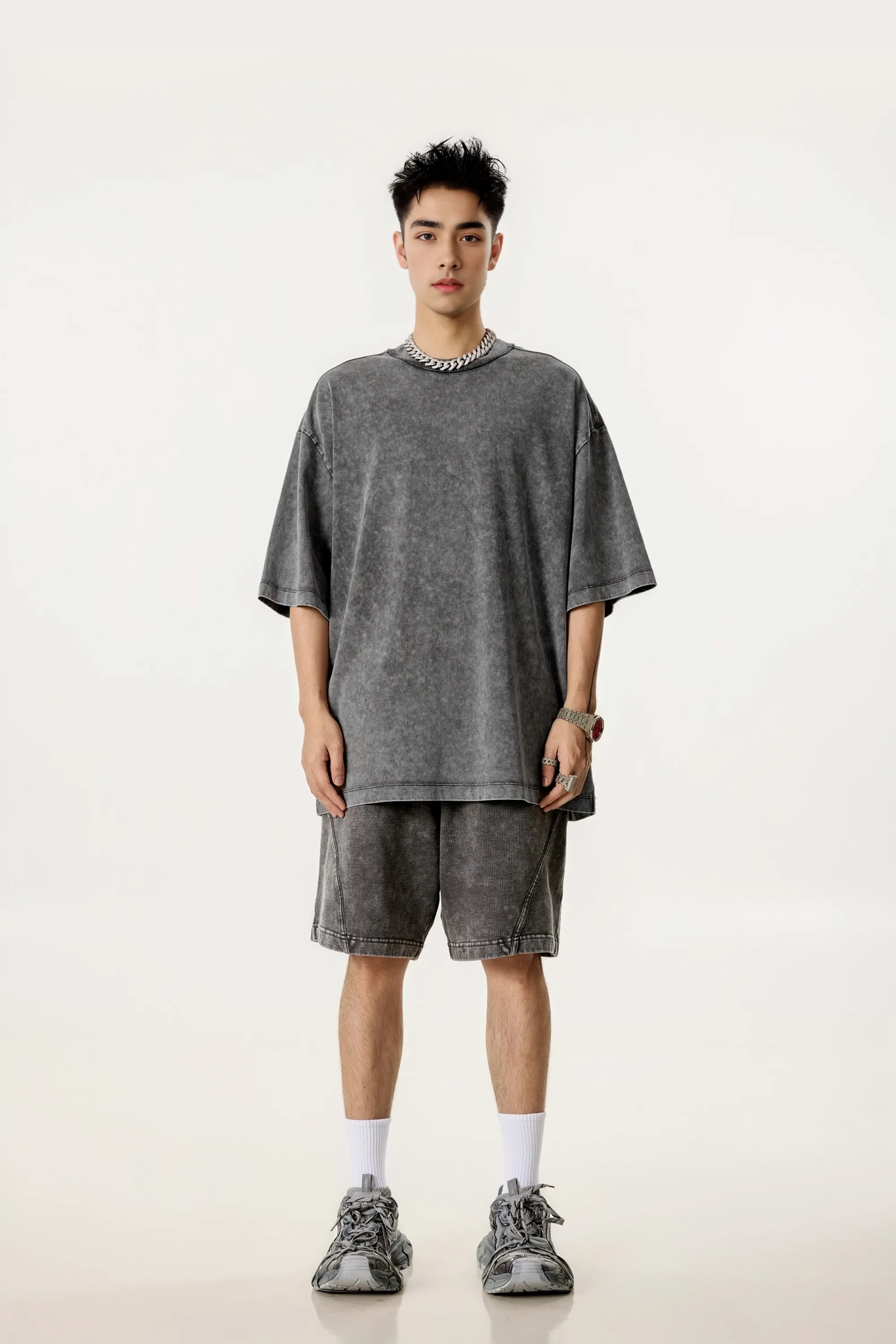 Man wearing a gray oversized t-shirt and shorts set on a white background