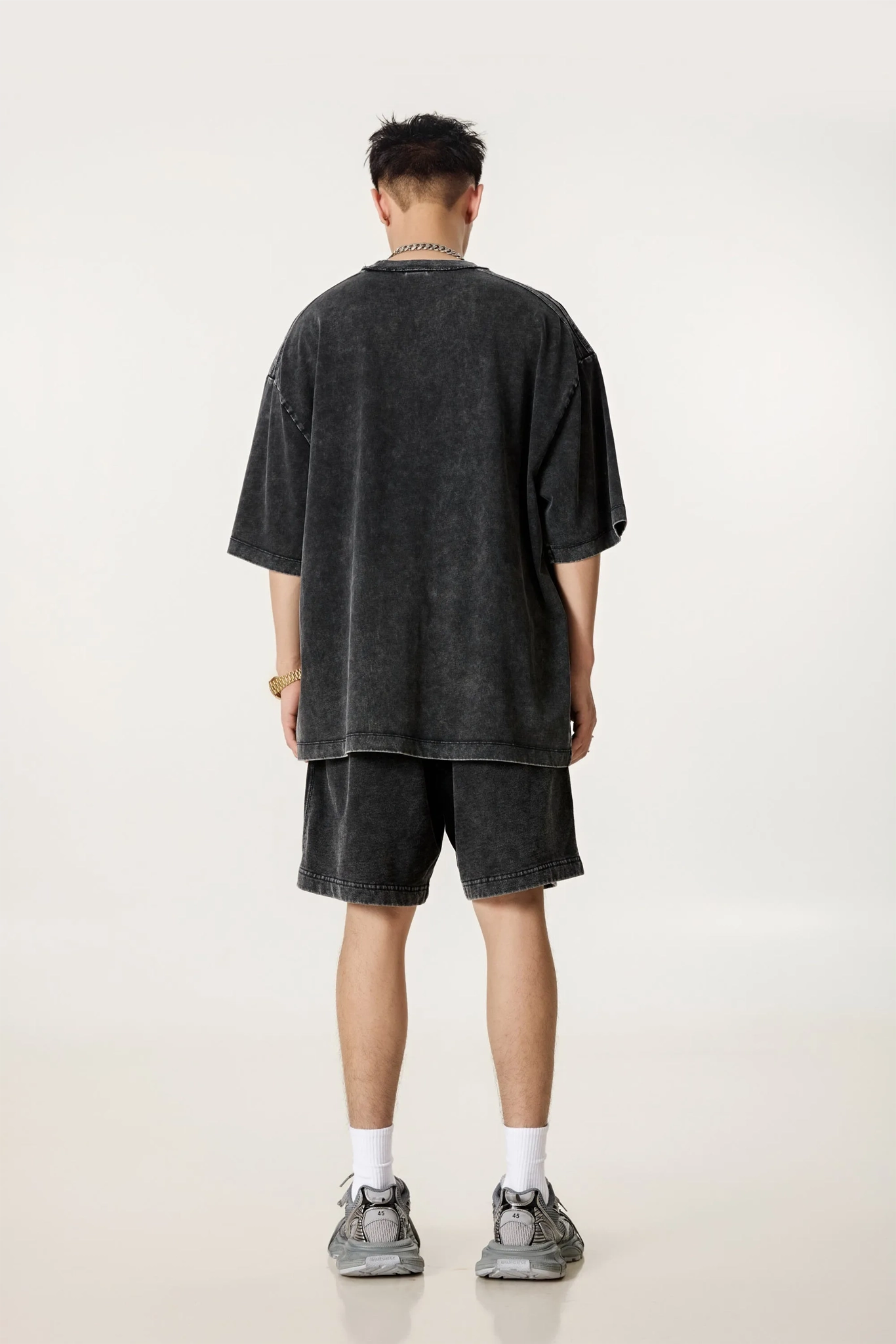 Person wearing a black oversized t-shirt and shorts set on a white background