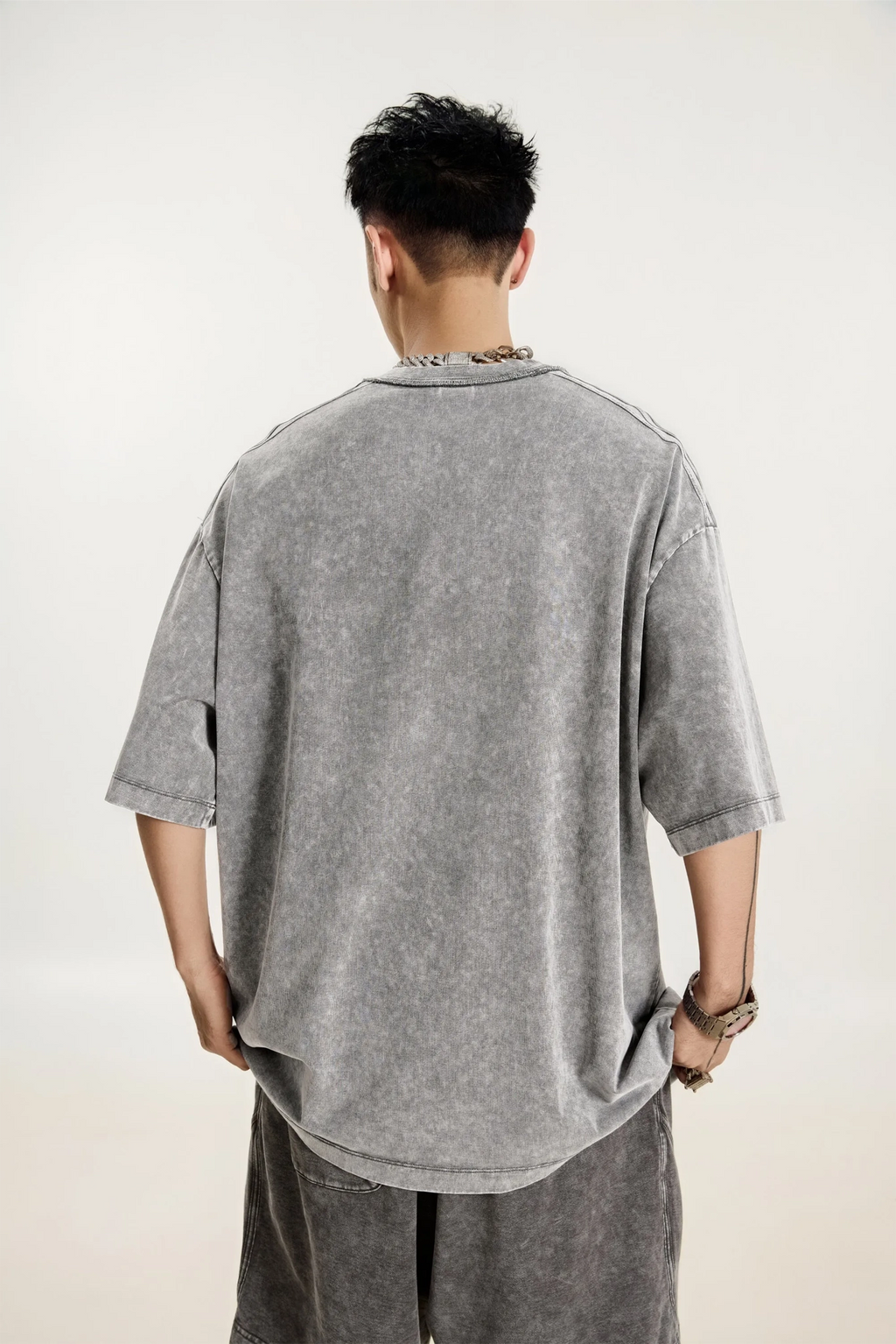 Person wearing a gray oversized t-shirt and pants on a plain background