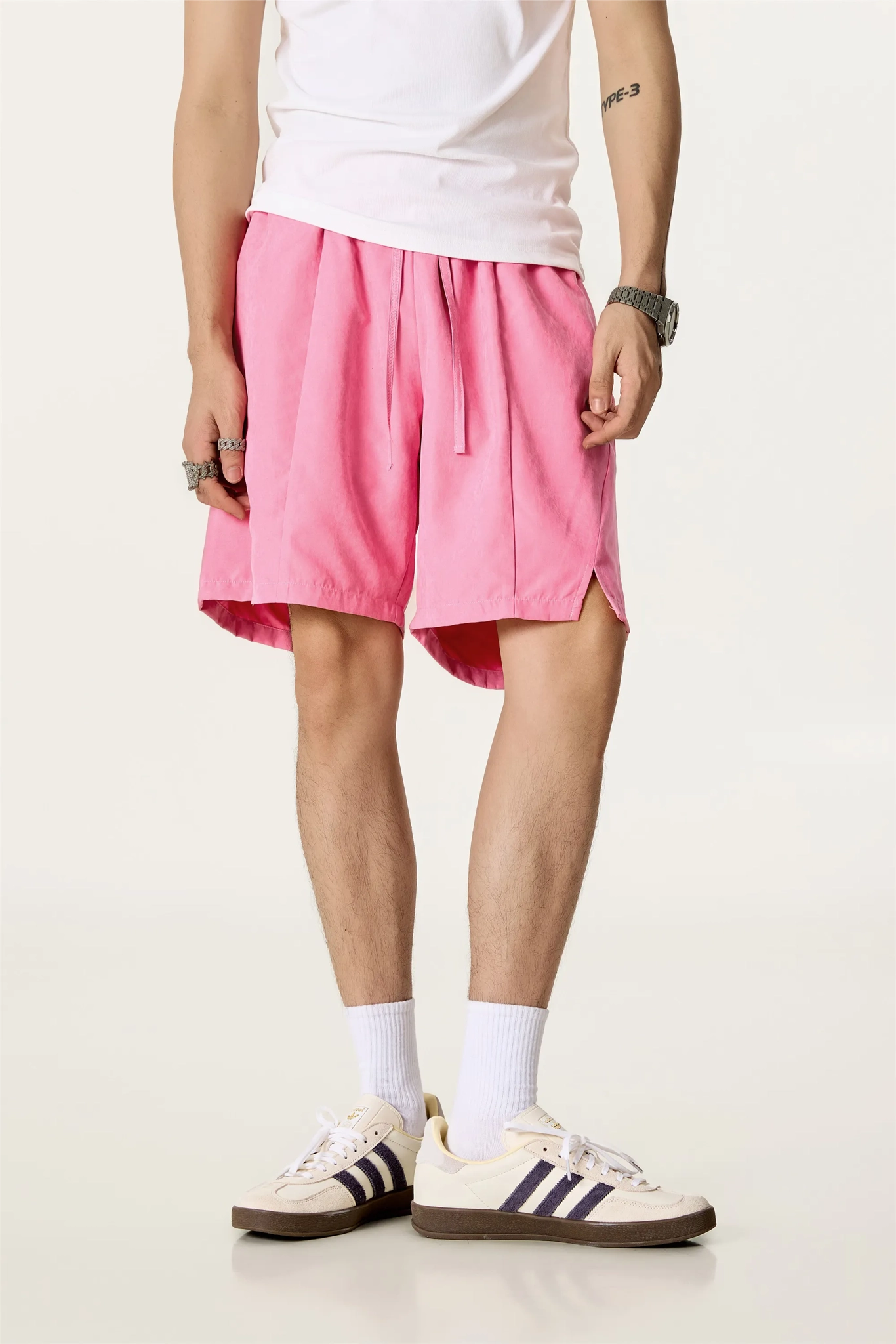Person wearing pink shorts and white sneakers on a plain background
