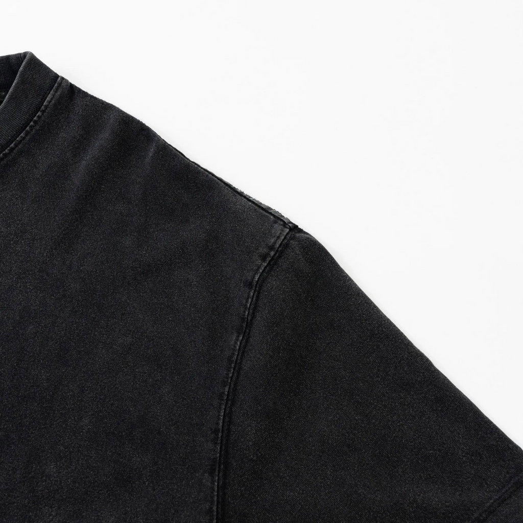 Close-up of a black denim jacket sleeve on a white background