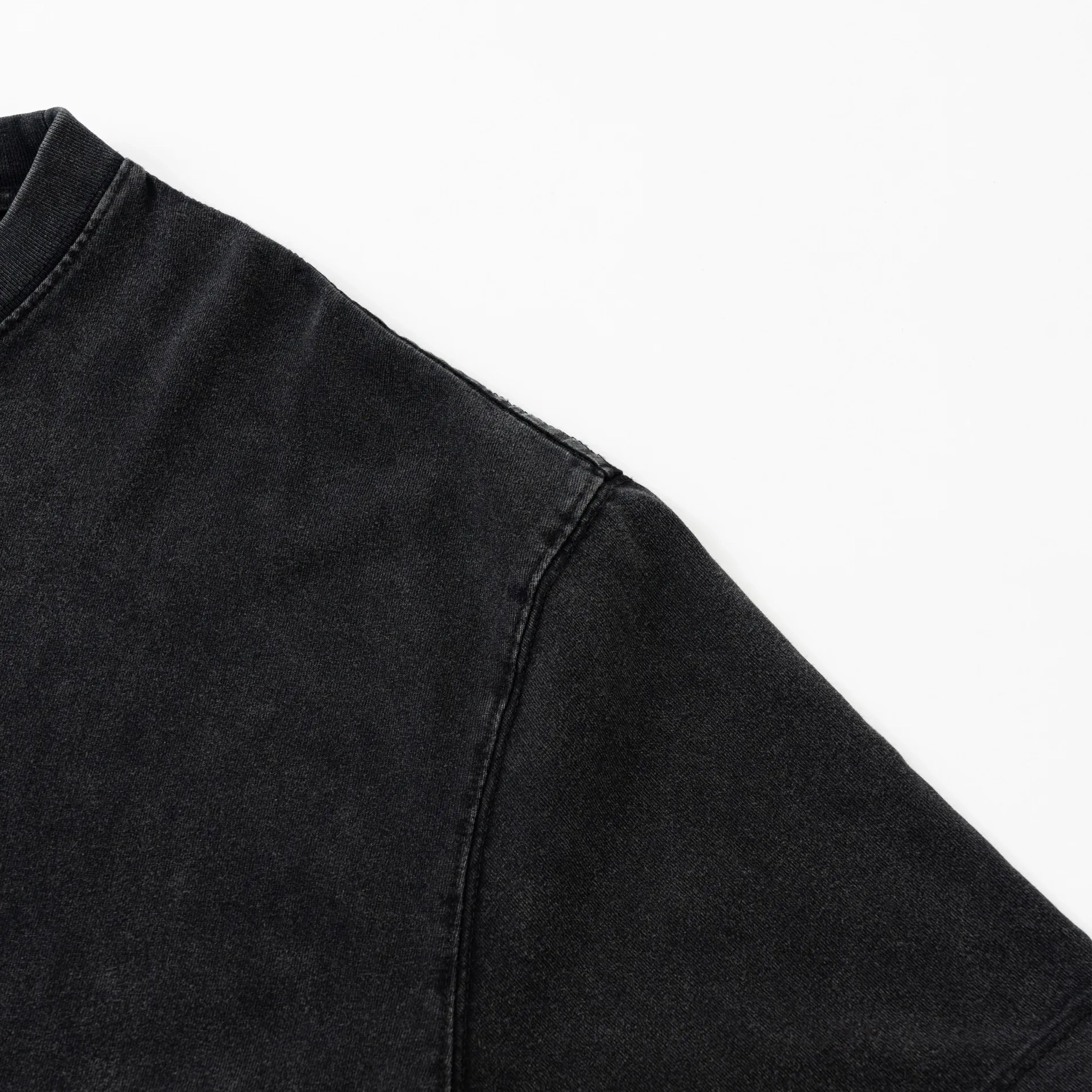 Close-up of a black denim jacket sleeve on a white background