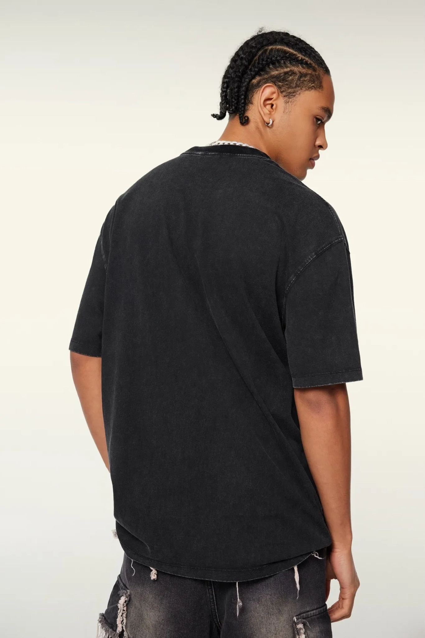 Person wearing a black t-shirt and dark pants on a plain background