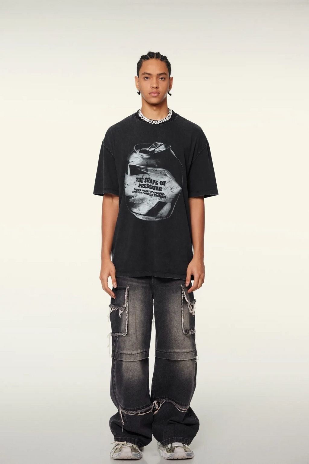 Person wearing a black t-shirt with graphic design and dark jeans on a white background