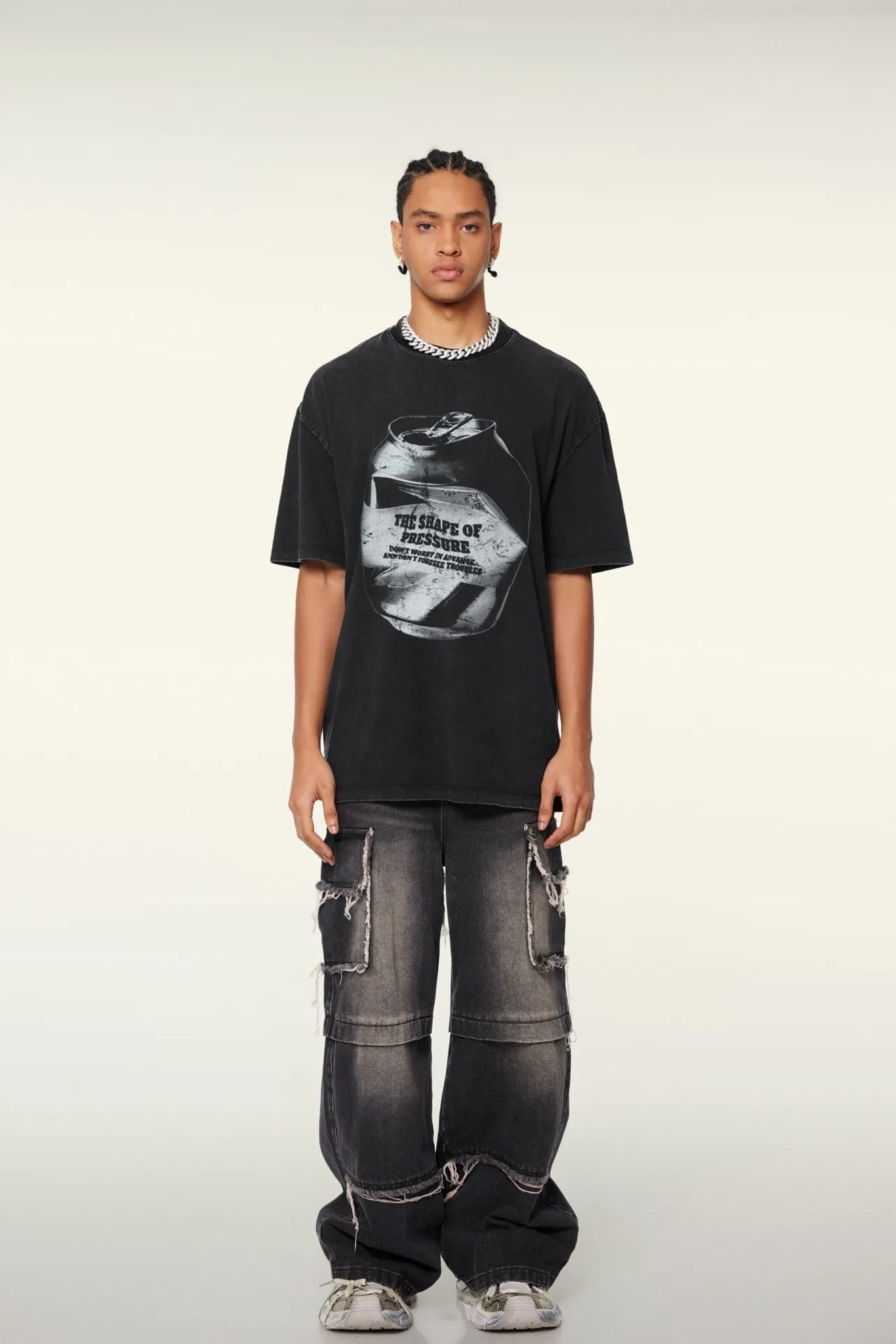 Person wearing a black t-shirt with graphic design and dark jeans on a white background