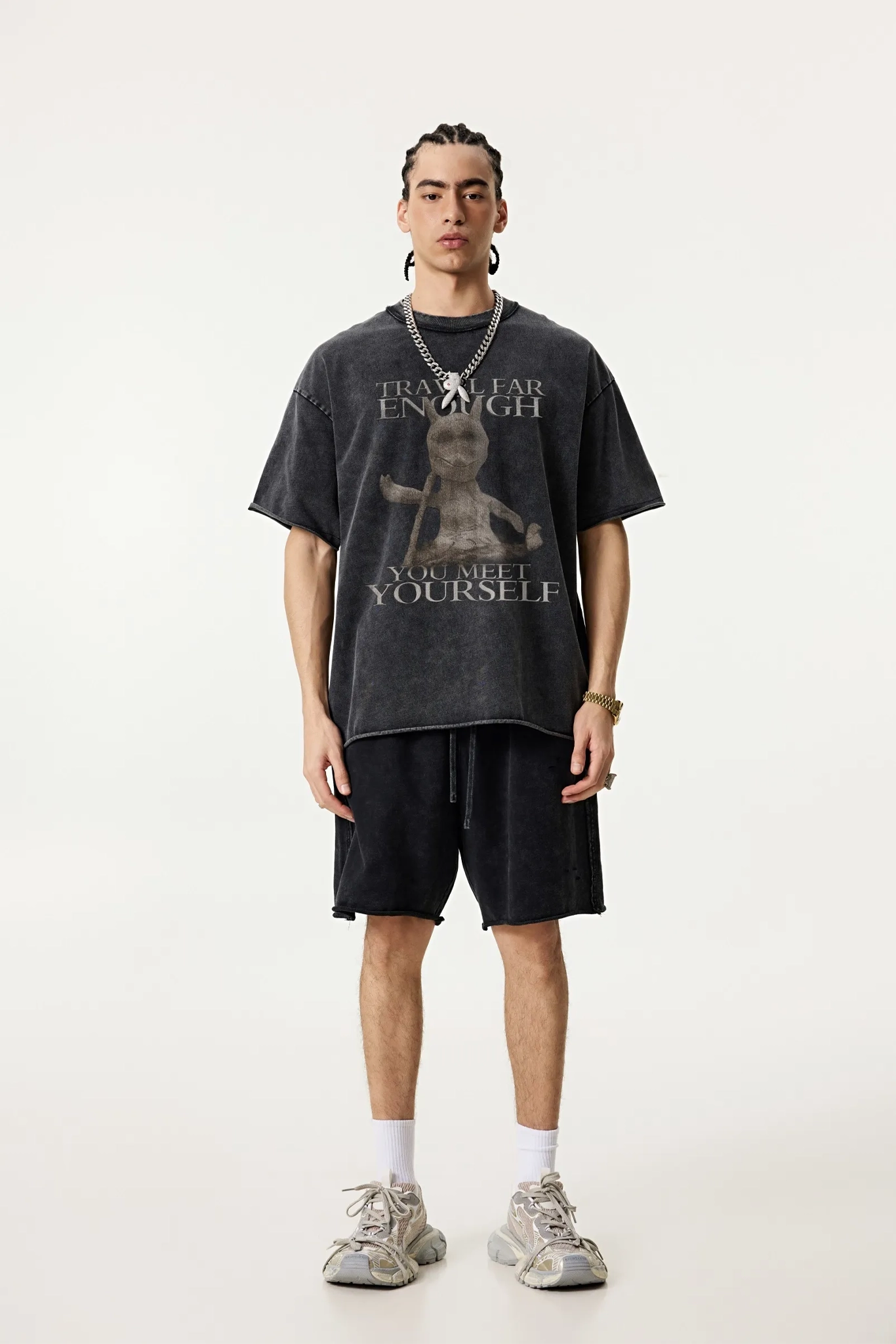 Person wearing a black graphic t-shirt and shorts on a white background