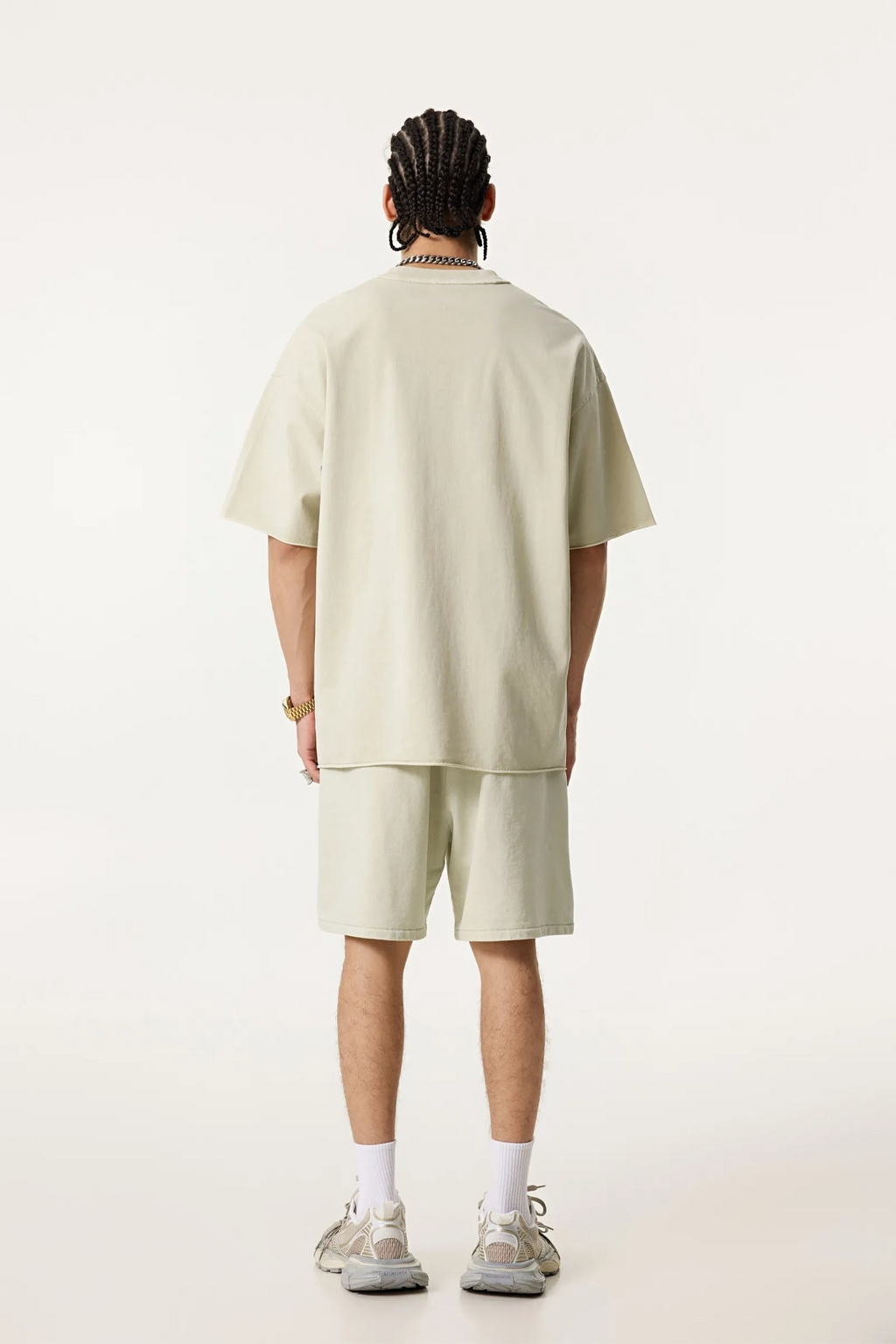 Person wearing a light-colored outfit with shorts on a white background