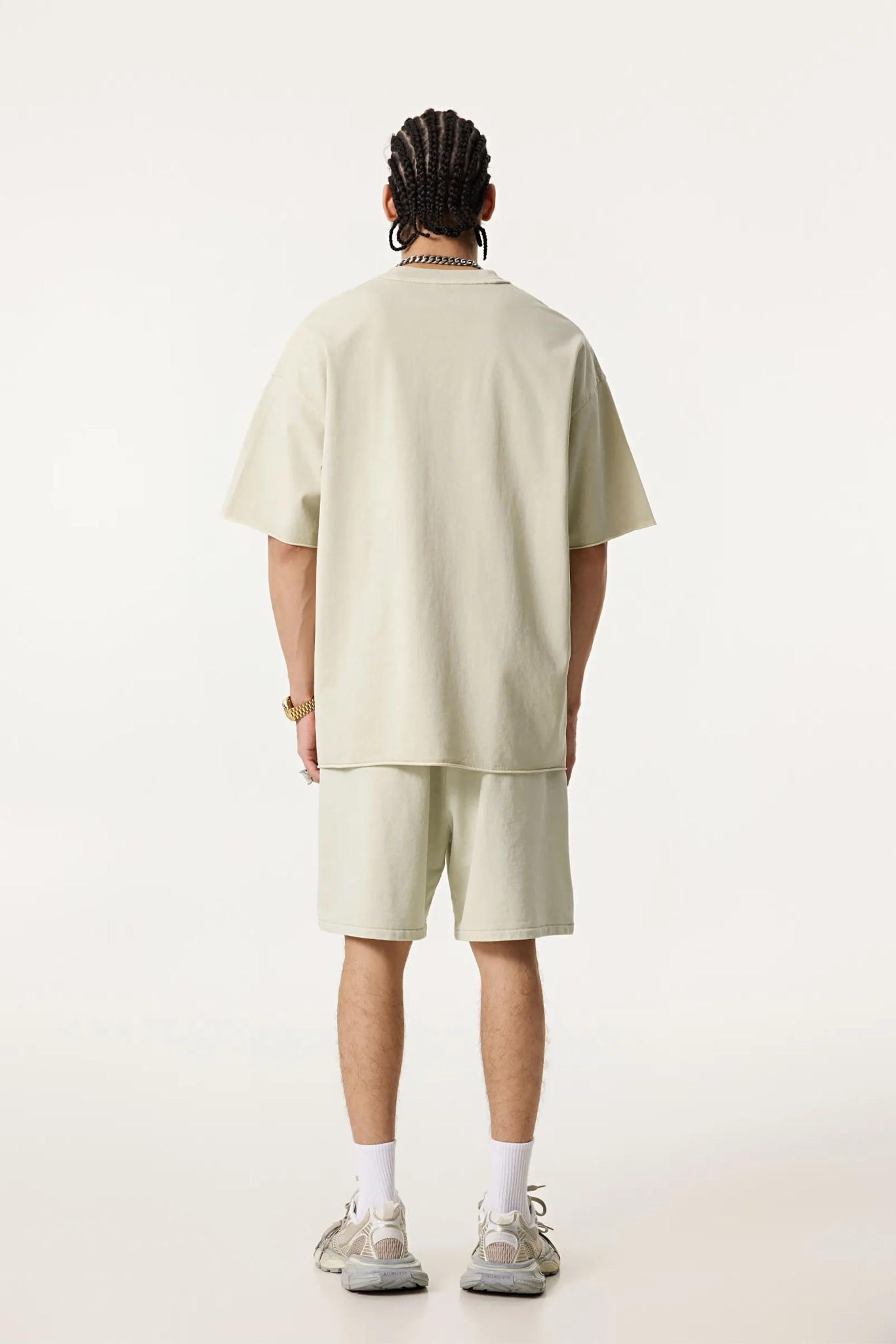 Person wearing a light-colored outfit with shorts on a white background