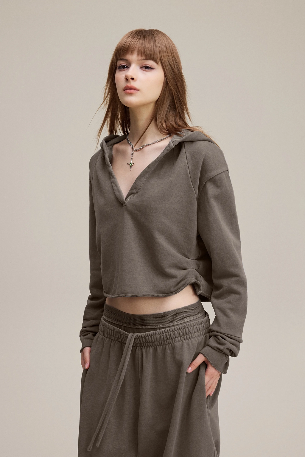 Woman wearing a green hoodie and pants on a plain background