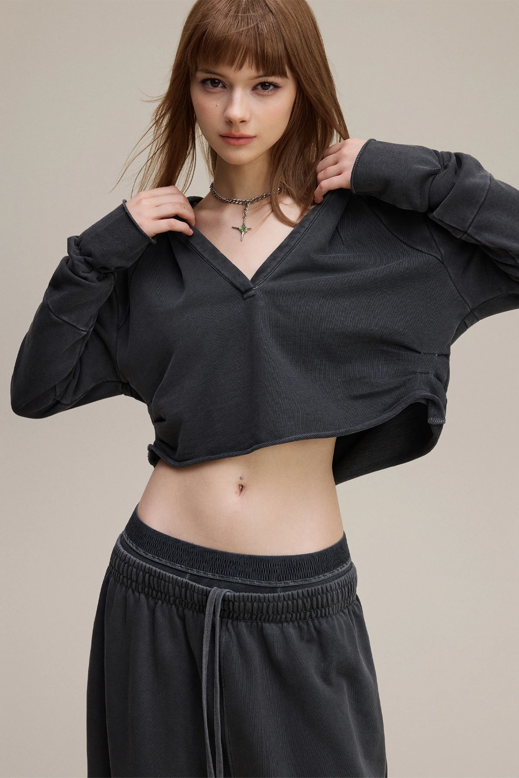 Woman wearing a black long-sleeve crop top and black pants on a beige background