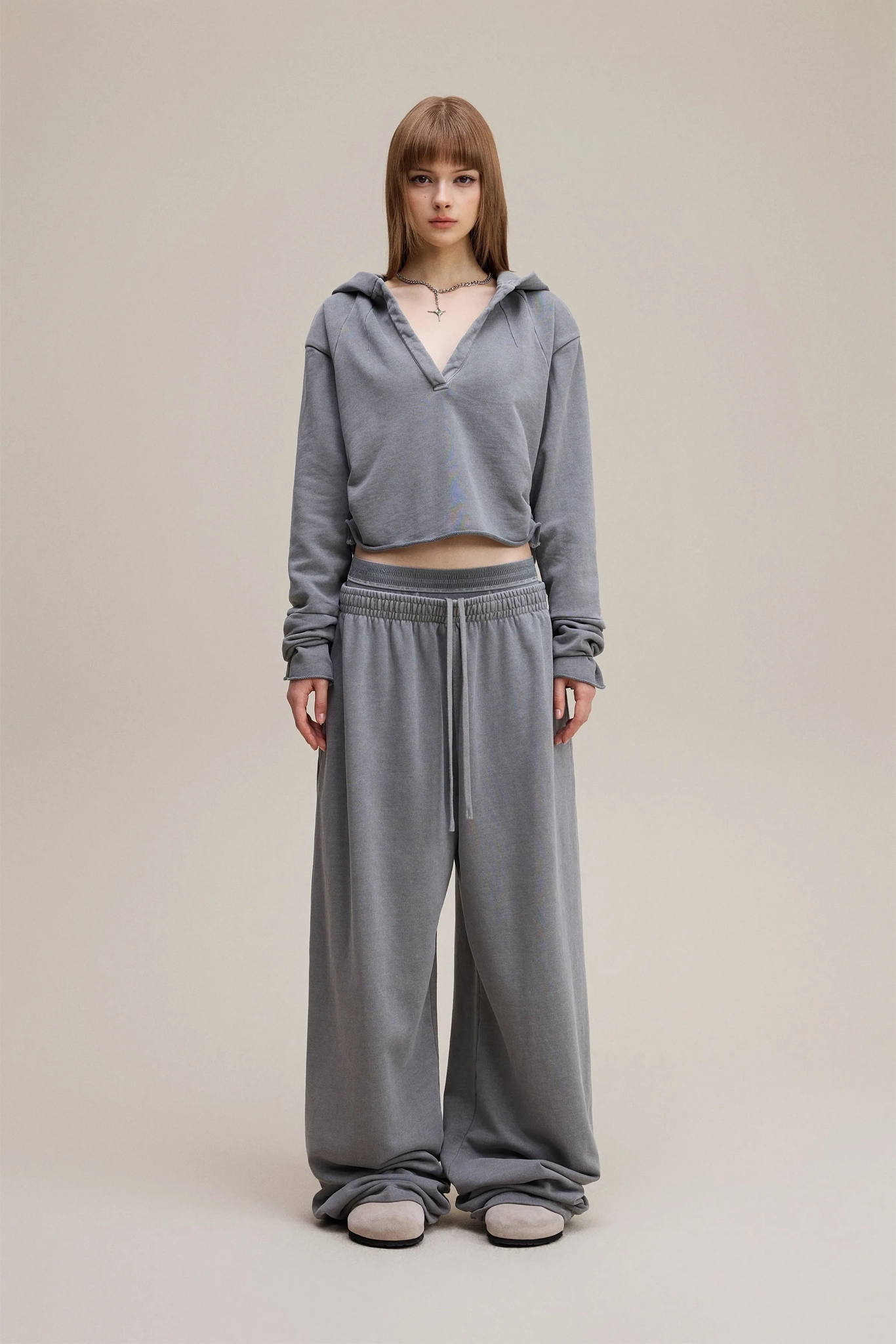 Person wearing a gray tracksuit on a plain background