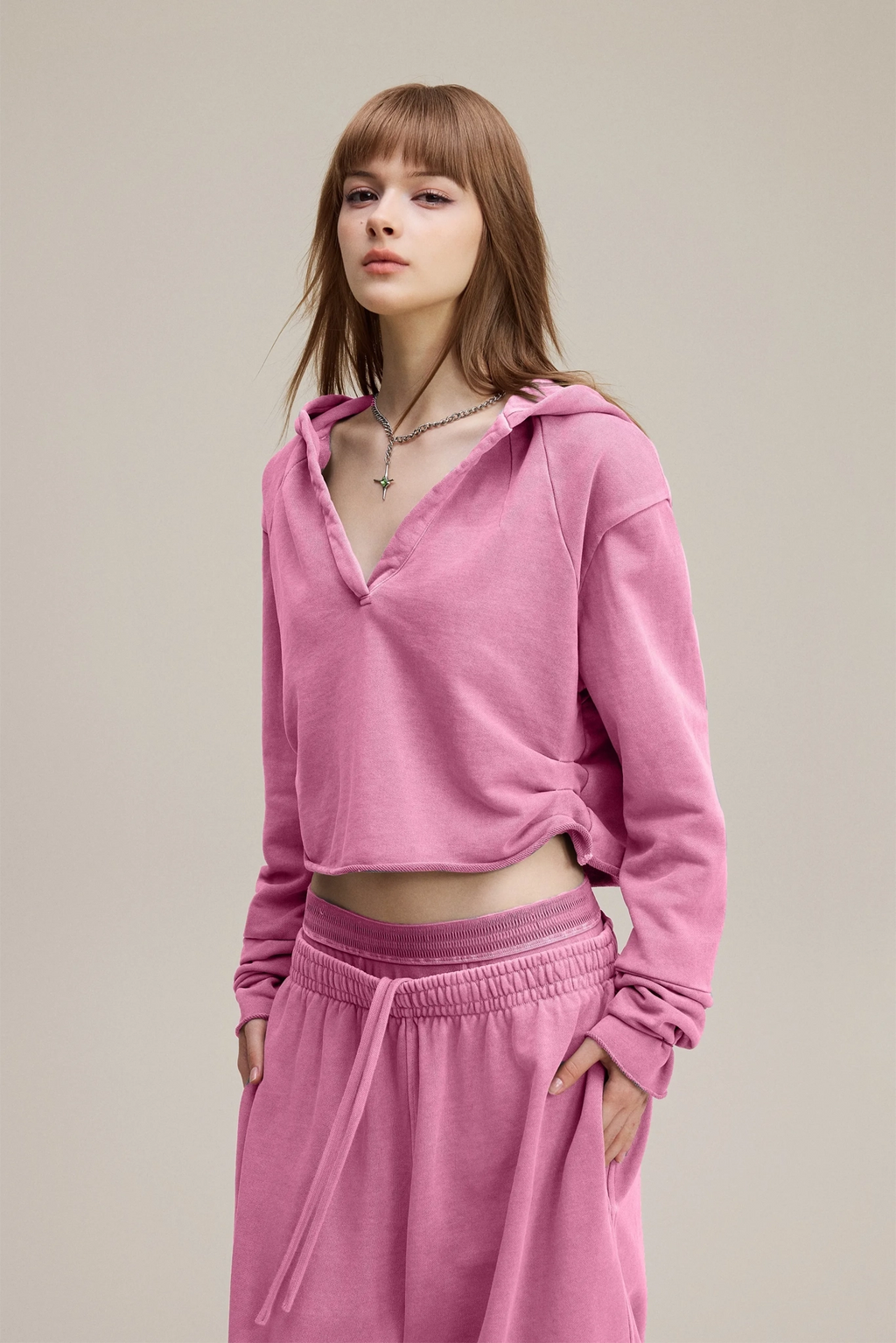Woman wearing a pink hoodie and pink pants on a beige background