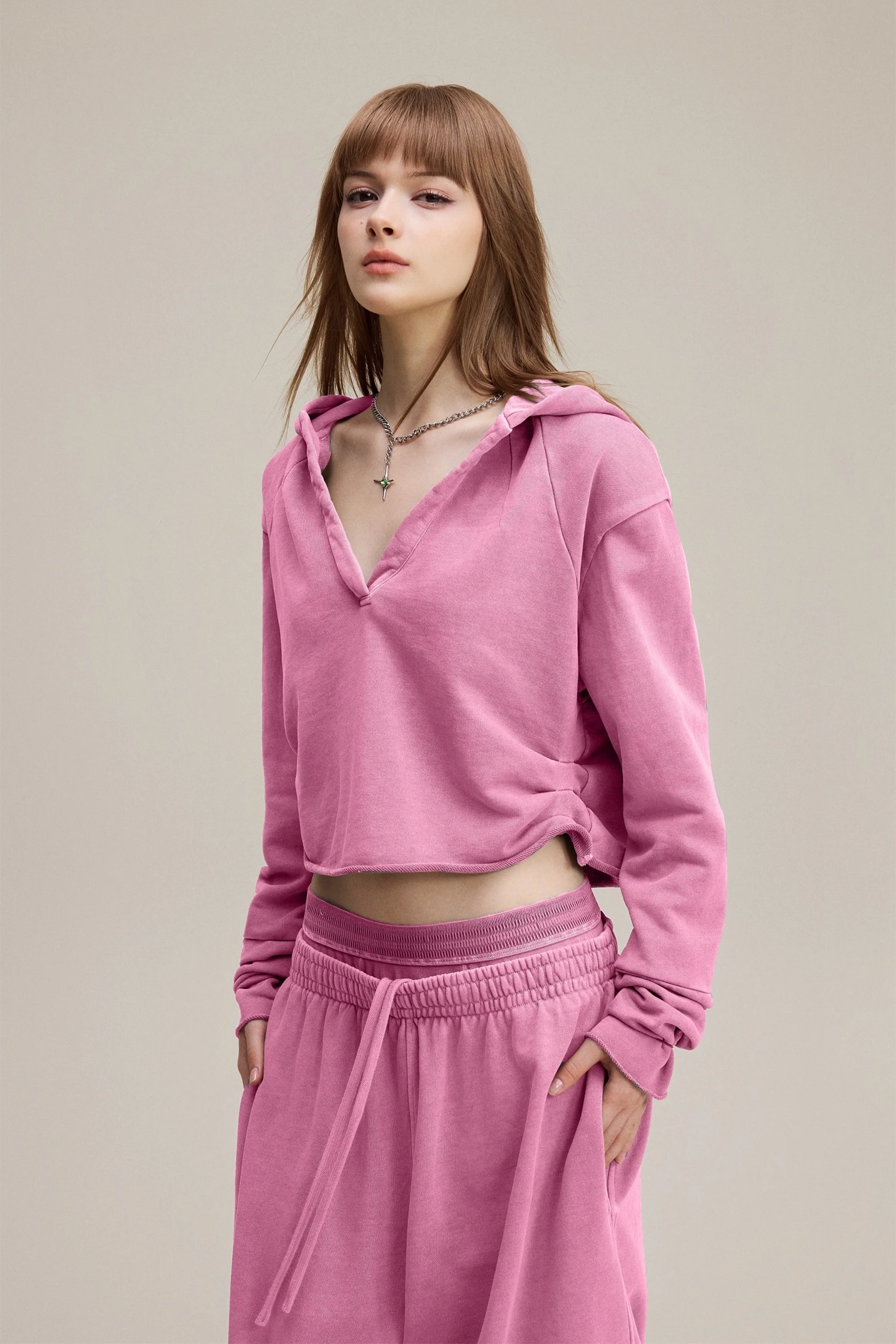 Woman wearing a pink hoodie and pink pants on a beige background