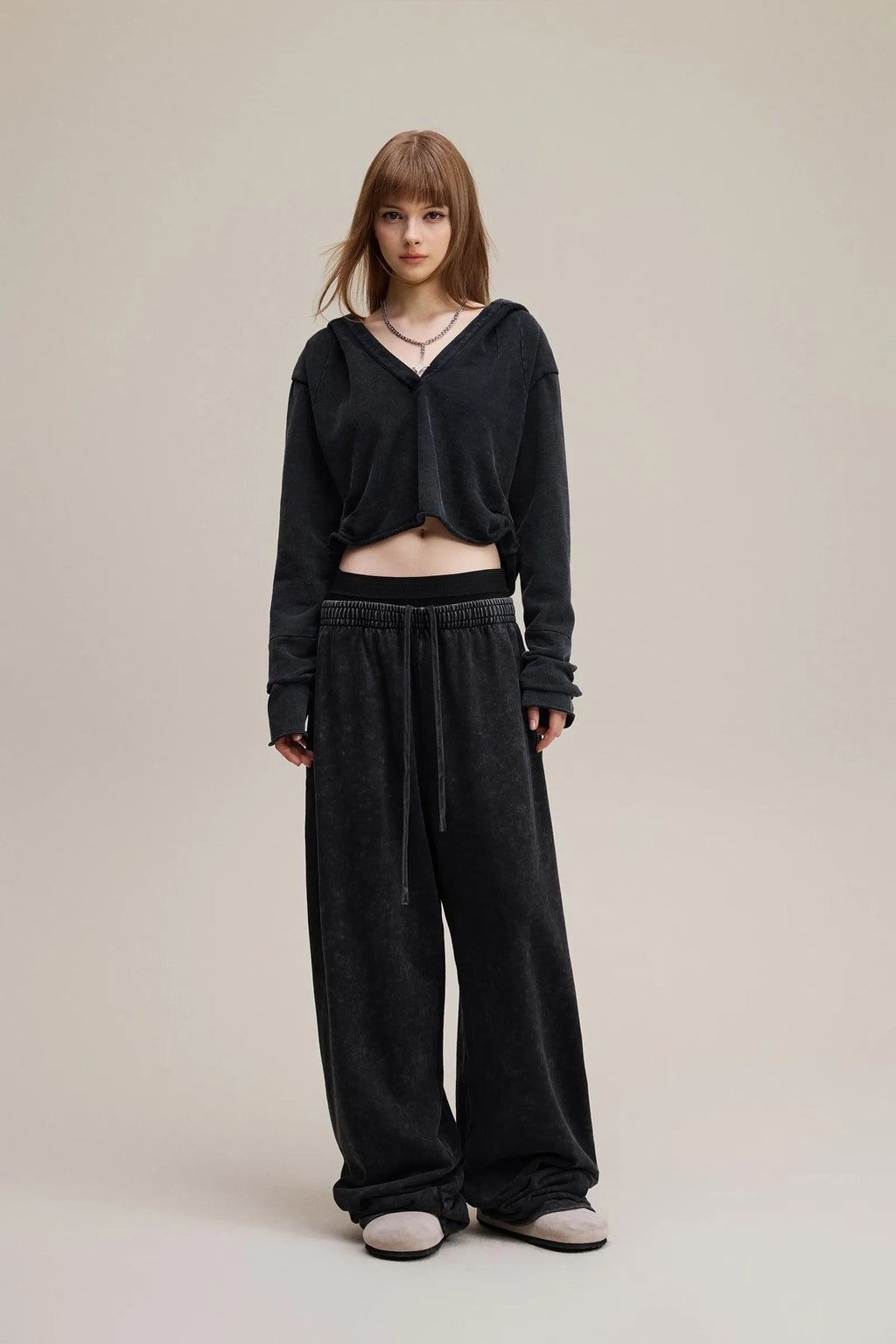 Person wearing a black outfit with wide-leg pants on a plain background