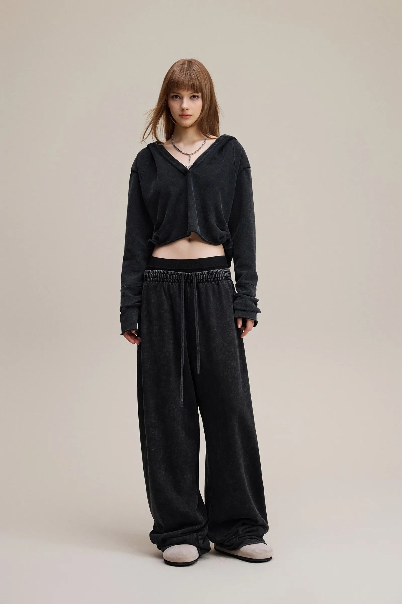 Person wearing a black outfit with wide-leg pants on a plain background